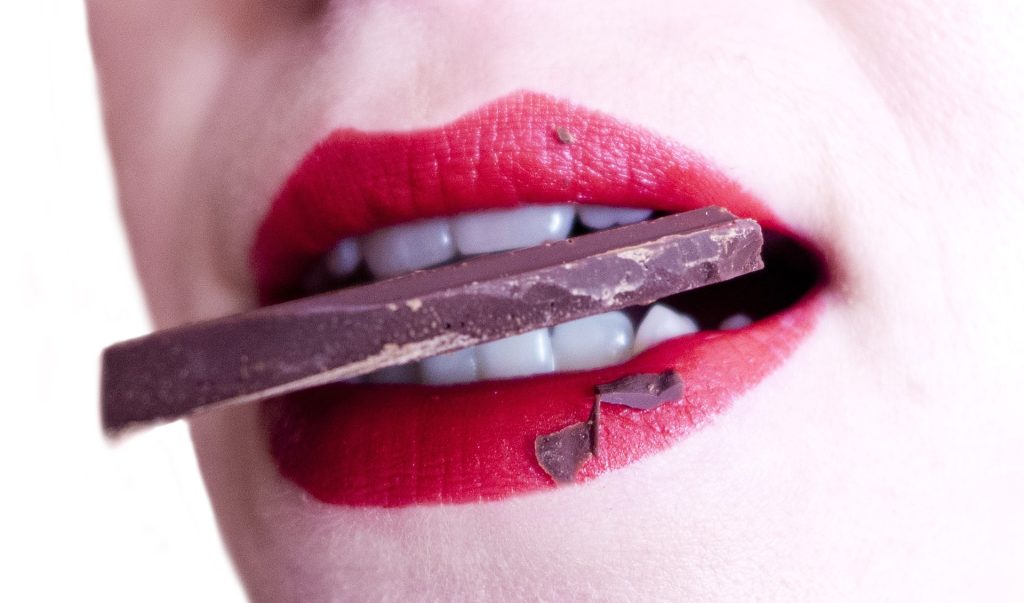 A woman biting into a piece of chocolate